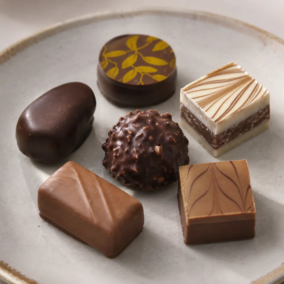 Sechs unterschiedliche Pralinen mit dokumentierten Formen und Schokoladenoberflächen im Detail