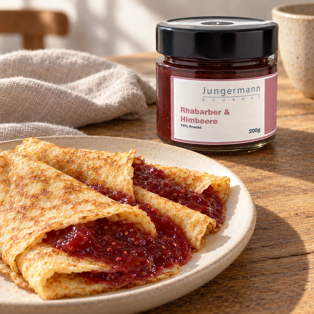 Crêpes mit Rhabarber-Himbeer-Aufstrich neben dem Originalglas. Serviervorschlag.
