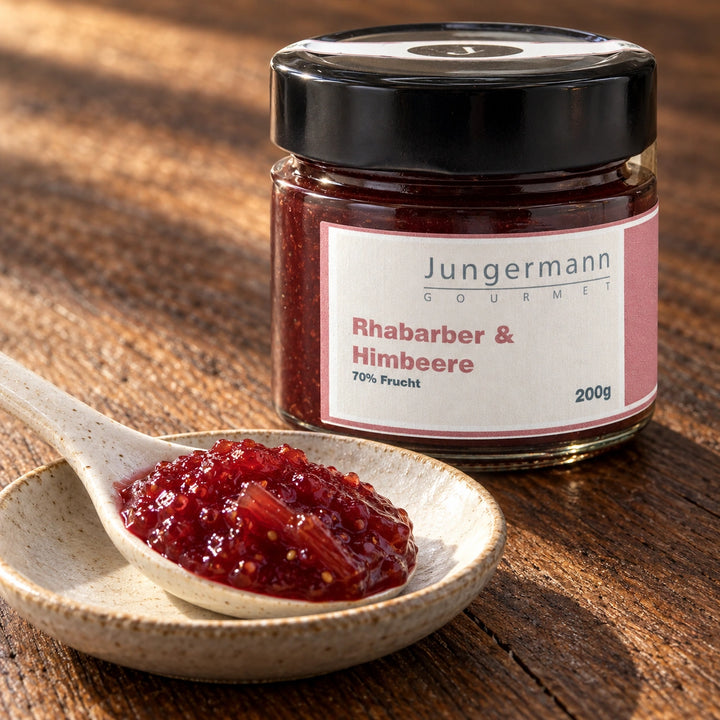 Nahaufnahme von Rhabarber-Himbeer-Aufstrich mit feinen Kernen und Fruchtfasern vor dem Originalglas.