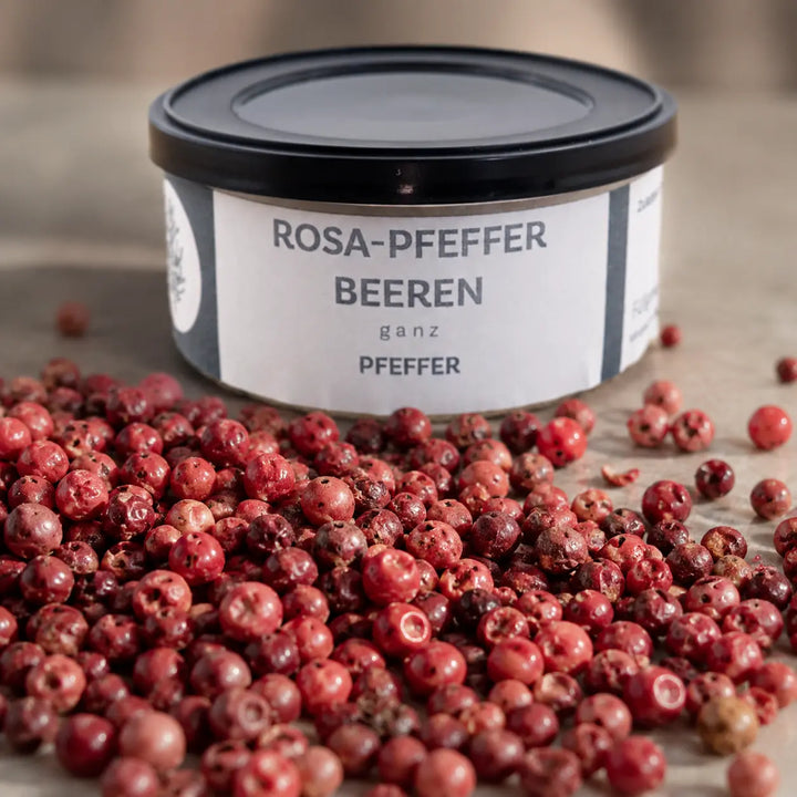 Ganze rosa Pfefferbeeren mit ihrer natürlichen Struktur vor der originalen Gewürzdose