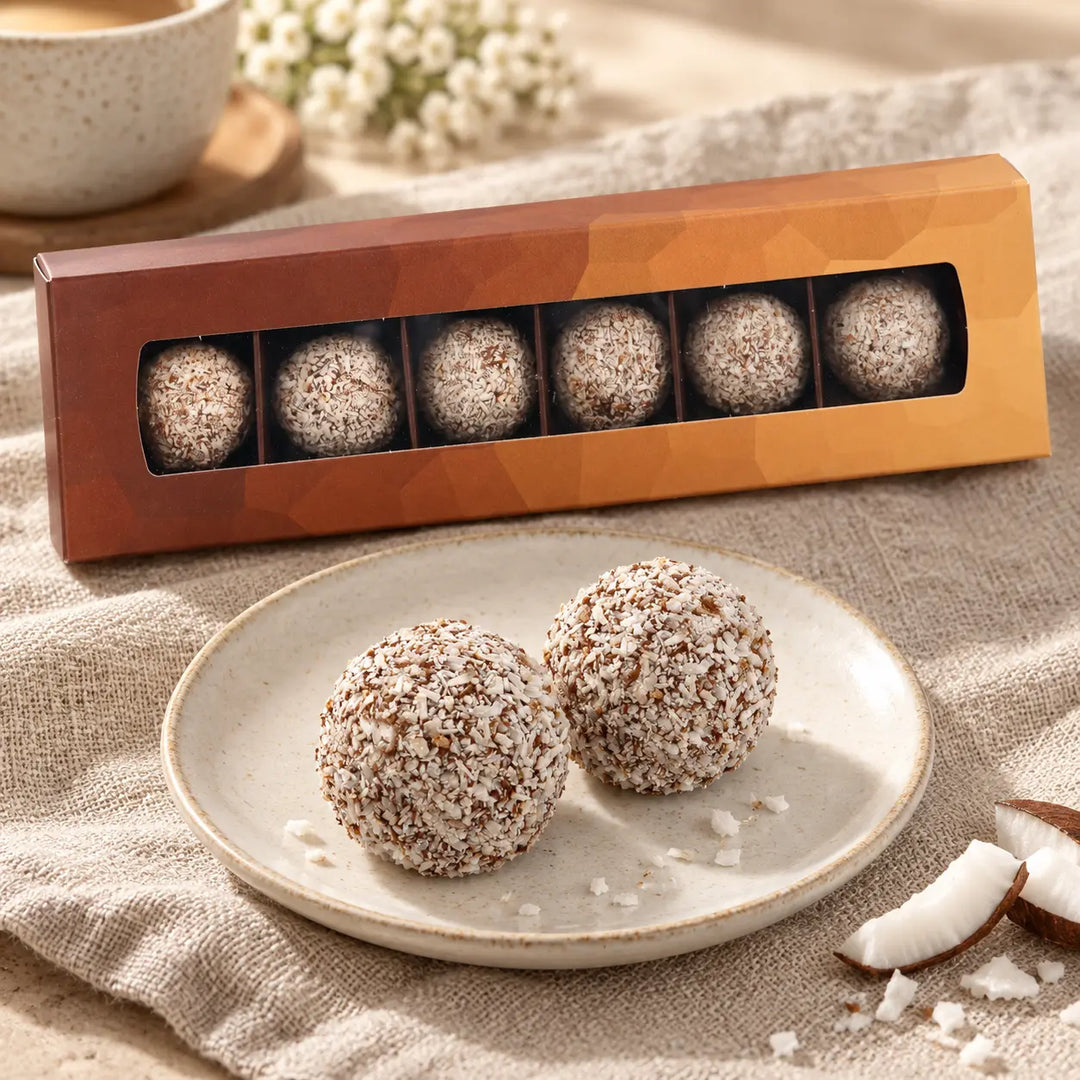 Rum-Cocos Trüffel auf einem Dessertteller mit der originalen Sechserbox im Hintergrund