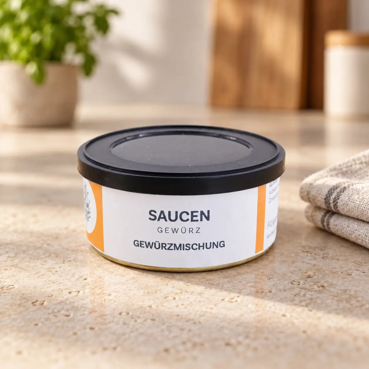 Saucengewürz in der flachen Originaldose mit orange-weißem Etikett und schwarzem Deckel auf einer hellen Arbeitsfläche.