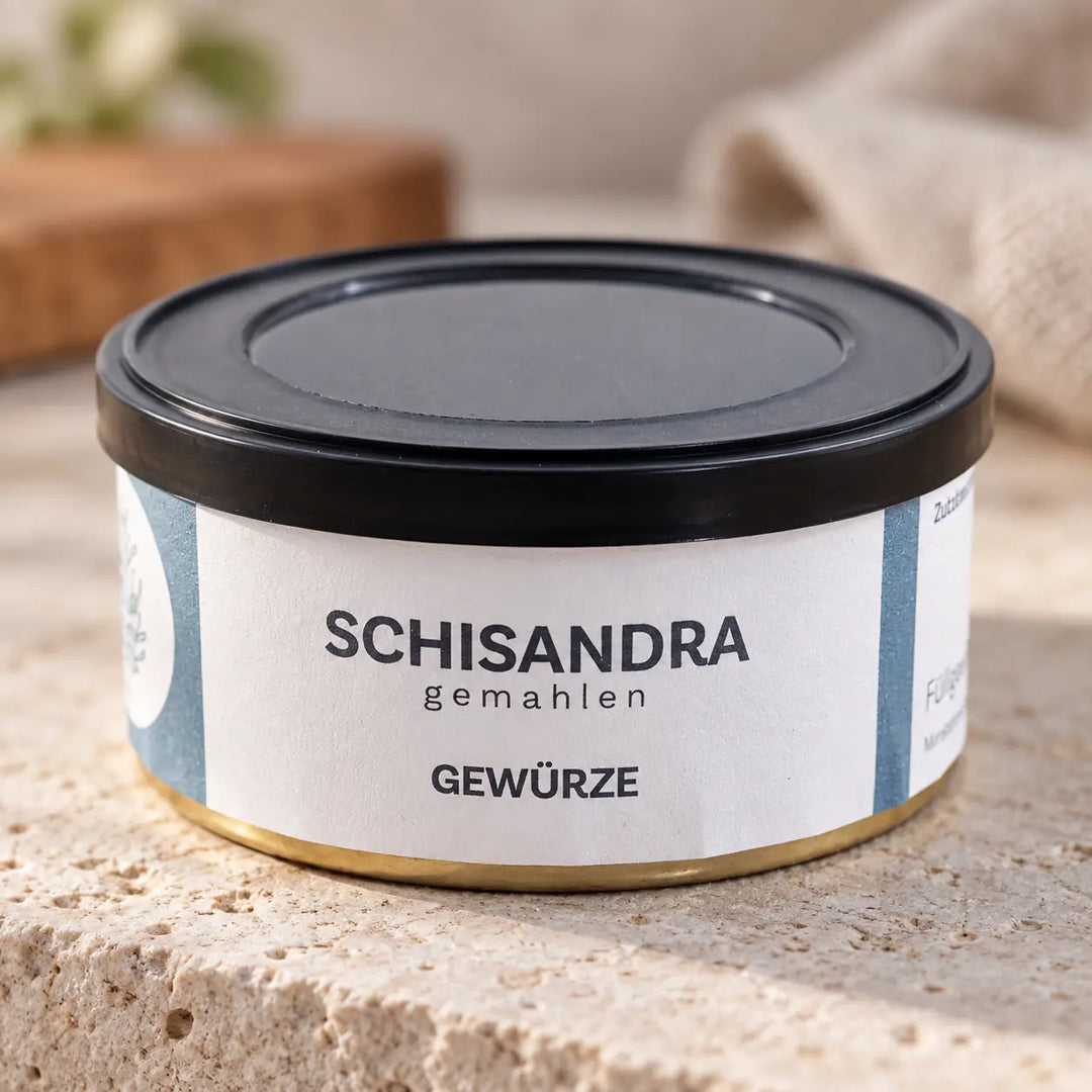 Nahaufnahme der Schisandra-Gewürzdose mit schwarzem Deckel, hellblau-weißem Etikett und goldfarbenem Bodenrand.