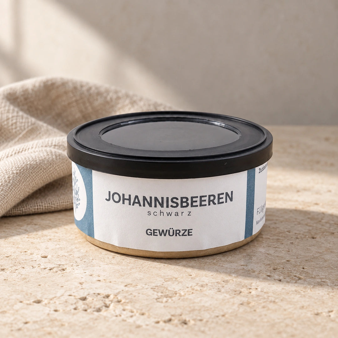 Originaldose Schwarze Johannisbeeren auf einer hellen Natursteinfläche neben einem Leinentuch.