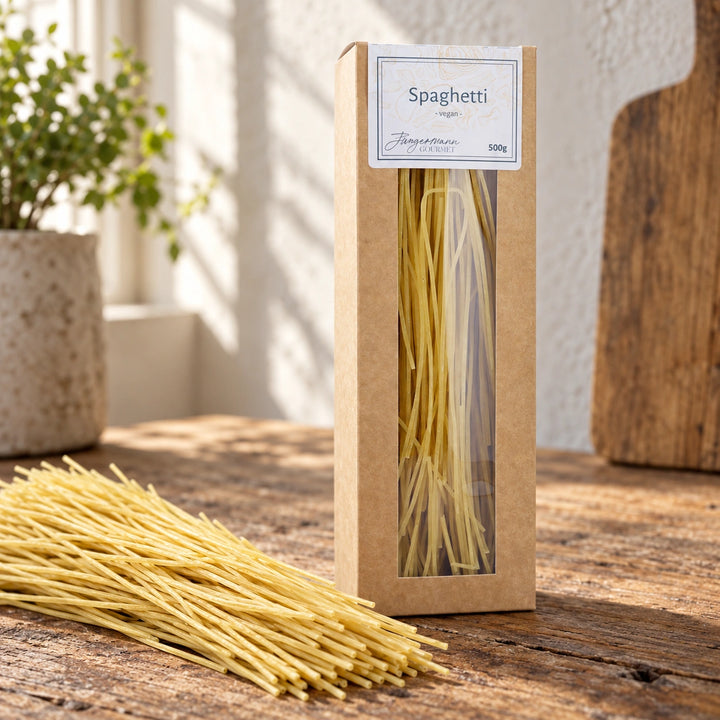 Helle, trockene Spaghetti neben der originalen Verpackung auf einem Holzbrett.