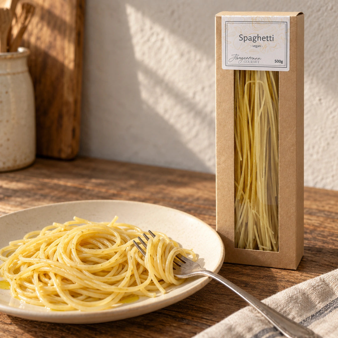 Eine kleine Spaghettigabel über dem Teller neben der Originalverpackung. Serviervorschlag.