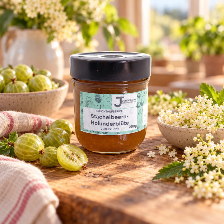 Stachelbeer-Holunderblüten Fruchtaufstrich im Originalglas auf rustikalem Holz mit grünen Stachelbeeren und Holunderblüten als Zutaten