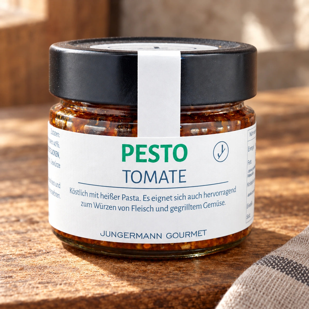 Tomatenpesto im Originalglas auf einer warmen Holzfläche mit Leinentuch.