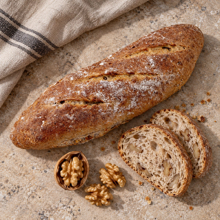 Walnuss-Baguette mit Walnusskernen neben einem Leinentuch.