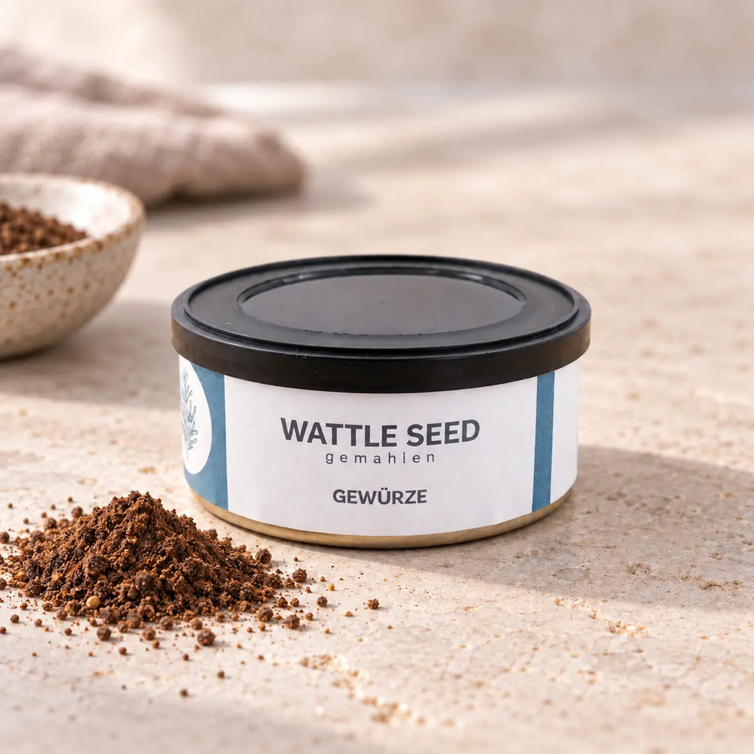 Wattle Seed gemahlen in flacher Gewürzdose mit blau-weißem Etikett auf hellem Naturstein