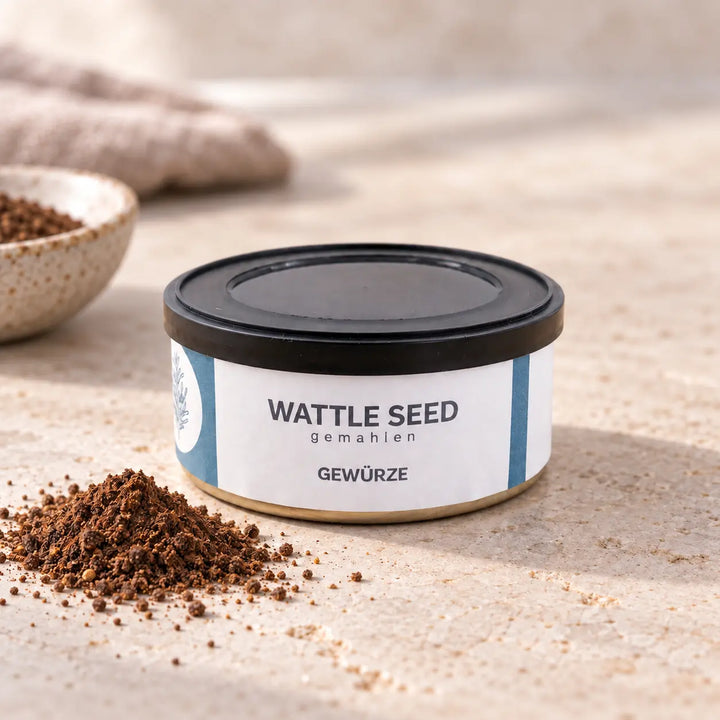 Wattle Seed gemahlen in flacher Gewürzdose mit blau-weißem Etikett auf hellem Naturstein